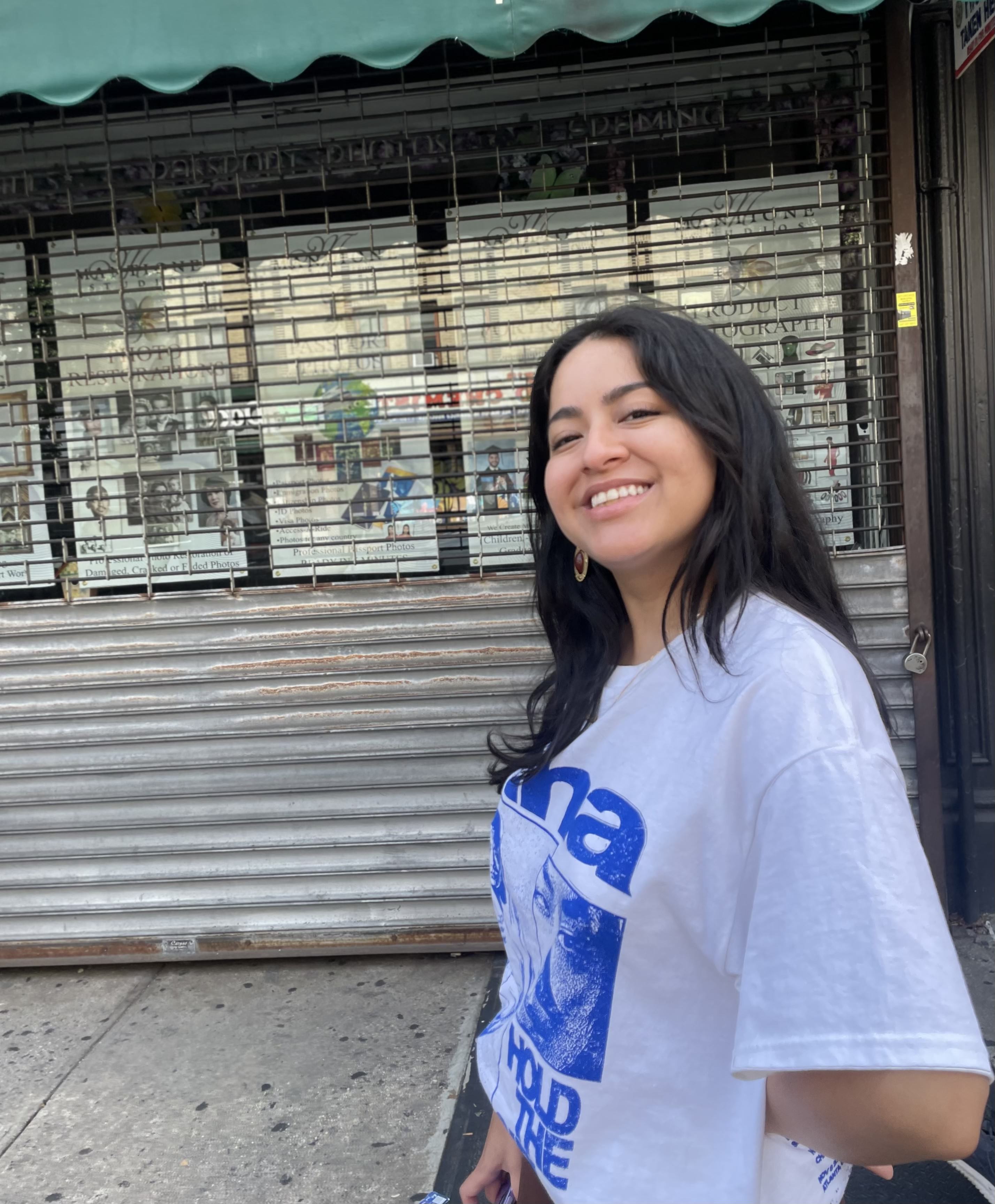 A photo of me, Julissa Zavala, smiling and standing in front of closed storefront in NYC